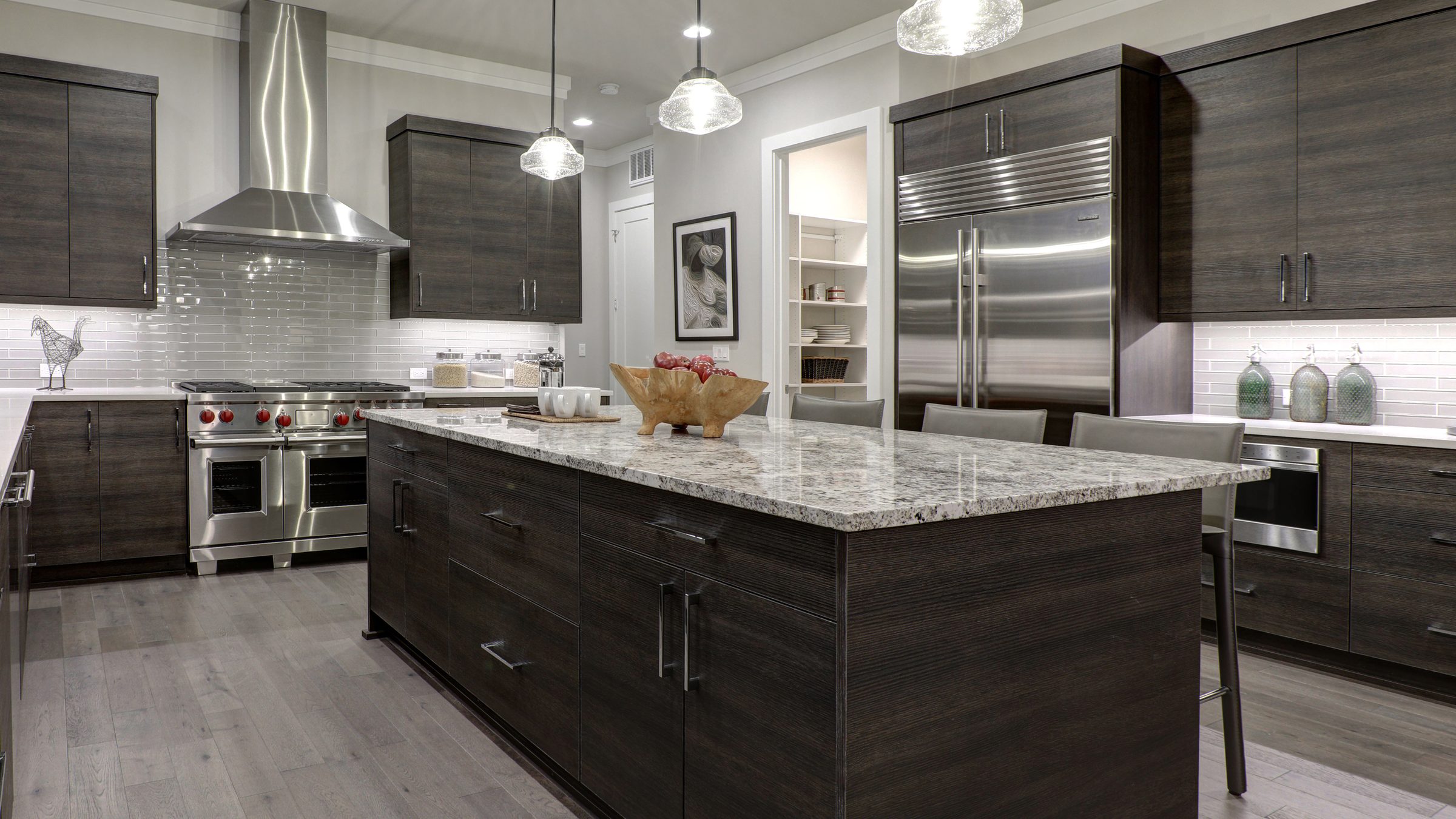 A modern kitchen with dark wood cabinetry, a granite island, and stainless steel appliances